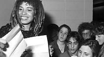 a smiling angela davis, holding documents, surrounded by female students.